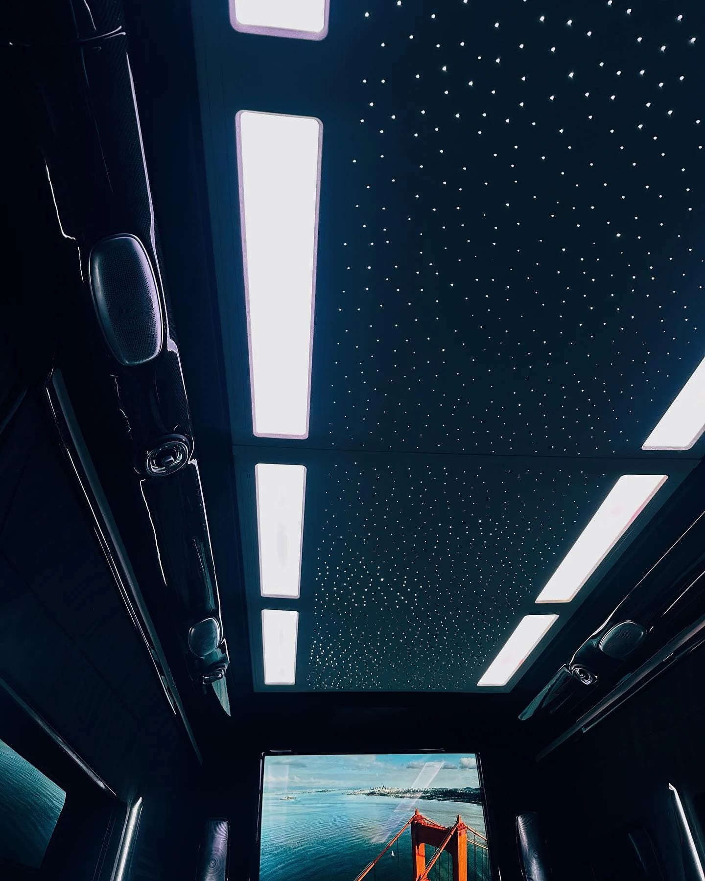 A starlight ceiling and white light panels above an entertainment screen